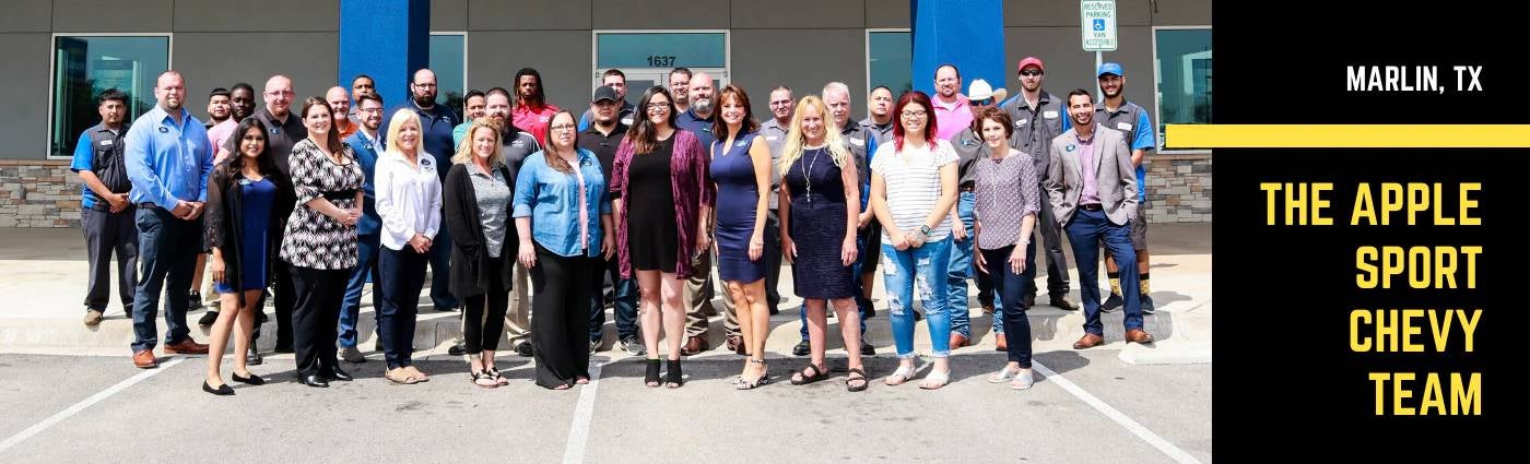 A group photo of the Apple Sport Chevy Team standing outside their dealership in Marlin, Texas.